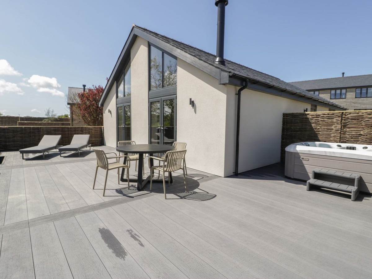 Garden House glazed gable with outdoor dining chairs, sun loungers and a hot tub