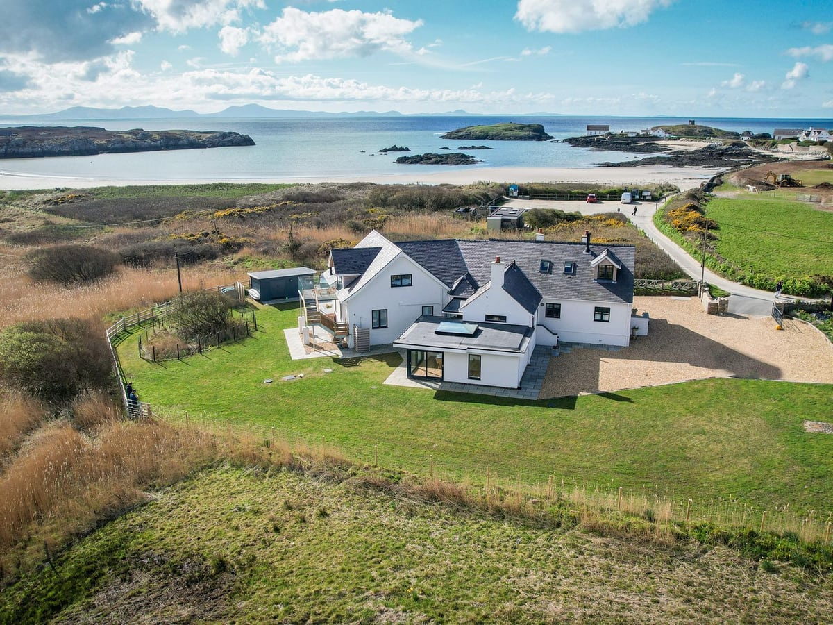 Glan Towyn house and lawn seen from above, with the bay and beach beyond the grounds