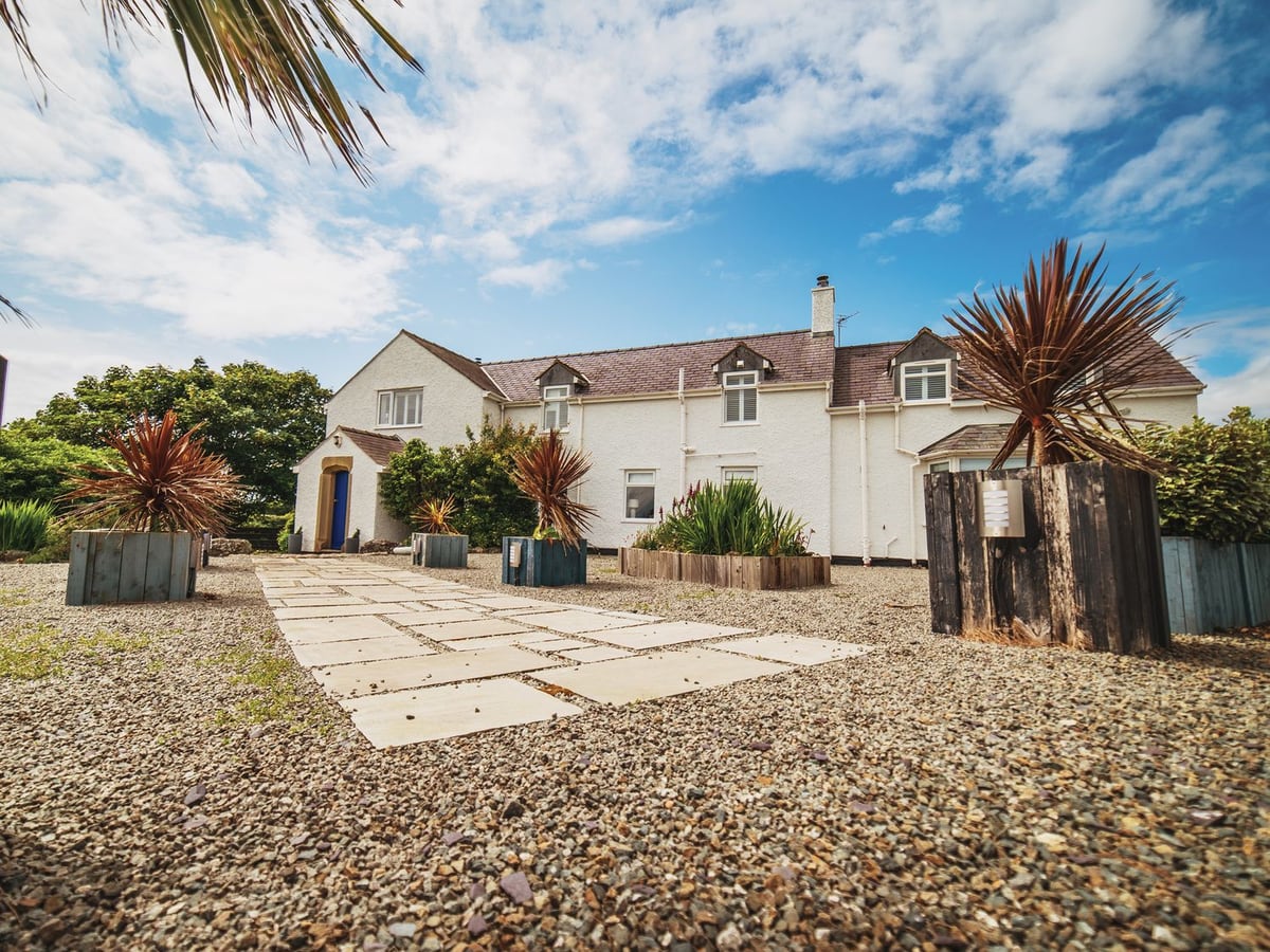 Glanllyn Bach white-painted exterior with a paved approach and gravel outdoor space
