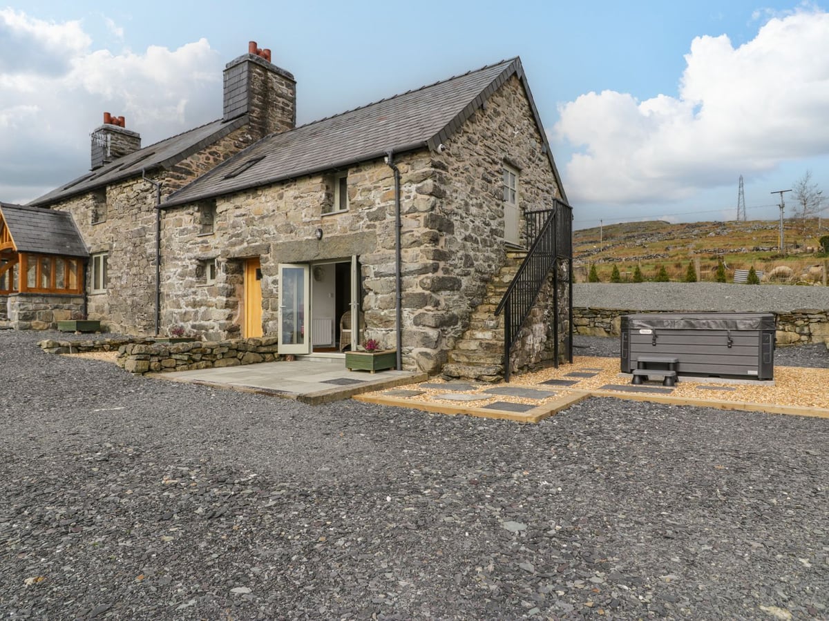 Hen Dy Craig Yr Ronwy stone cottage with patio, gravel yard and hot tub with its lid on