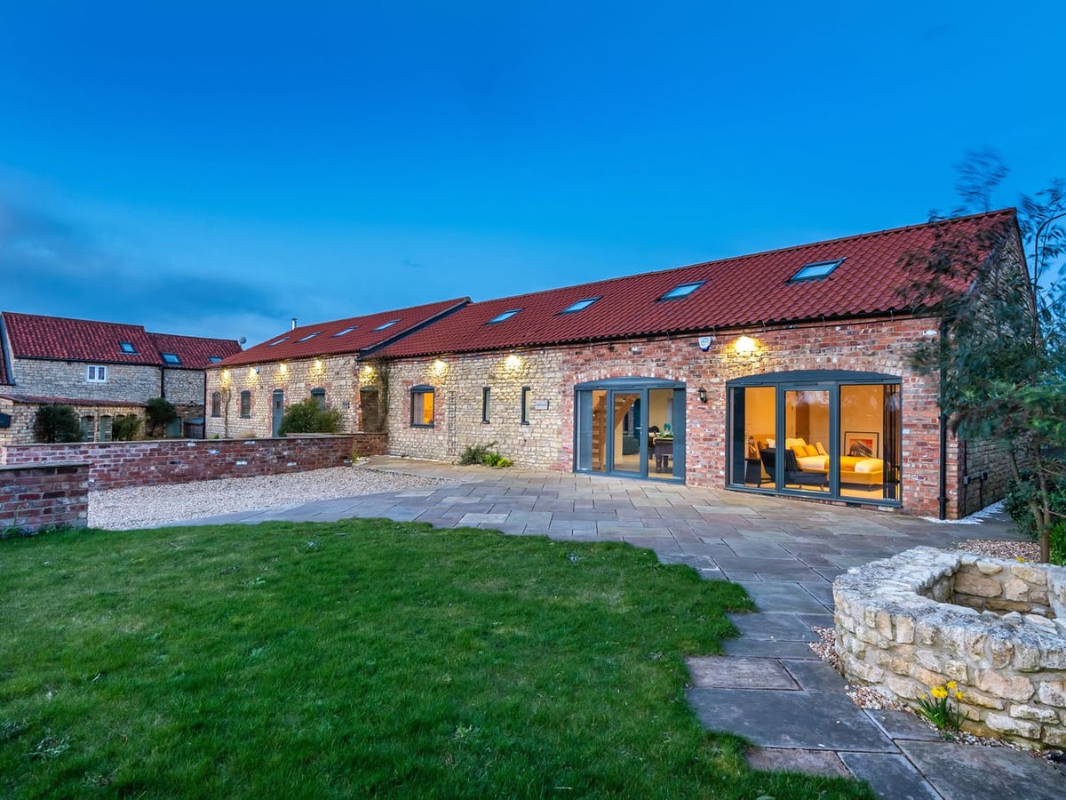 Stone exterior of Hideaway facing a lawn and paved patio at dusk