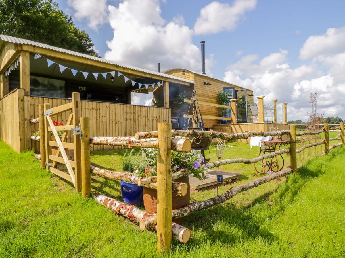 High Rigg Shepherd's Retreat timber hut and covered deck behind a rustic rail fence