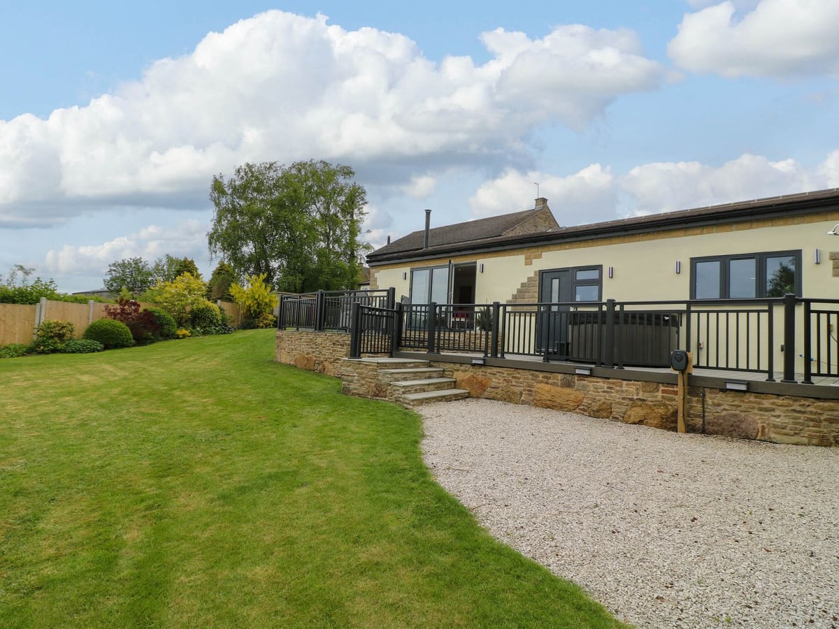 Highview Stables with a lawn, raised terrace, black railings and steps to the cottage