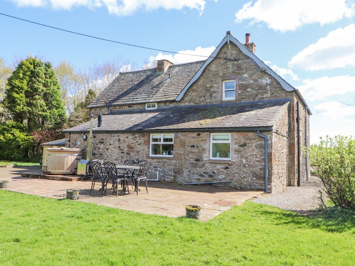 Home Farm House stone exterior with a lawn, patio table and wooden hot tub beside the wall