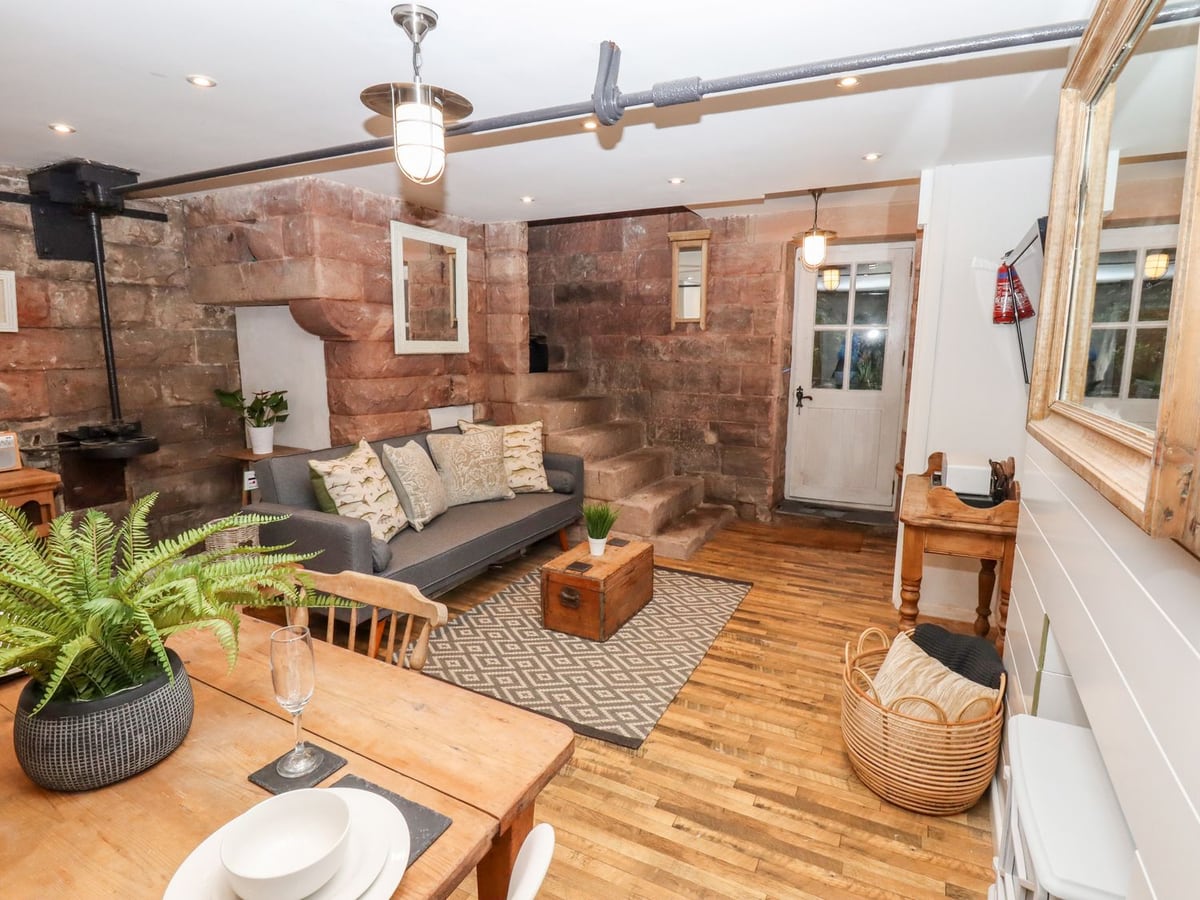 Grey sofa, stone walls and wooden flooring in the living room at Horton Lodge Boathouse.