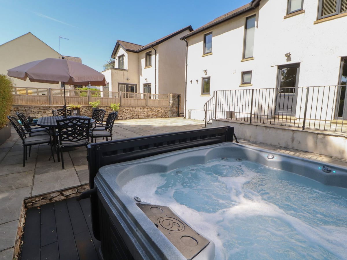 Ingleborough hot tub beside a paved dining terrace and cream walls with black railings