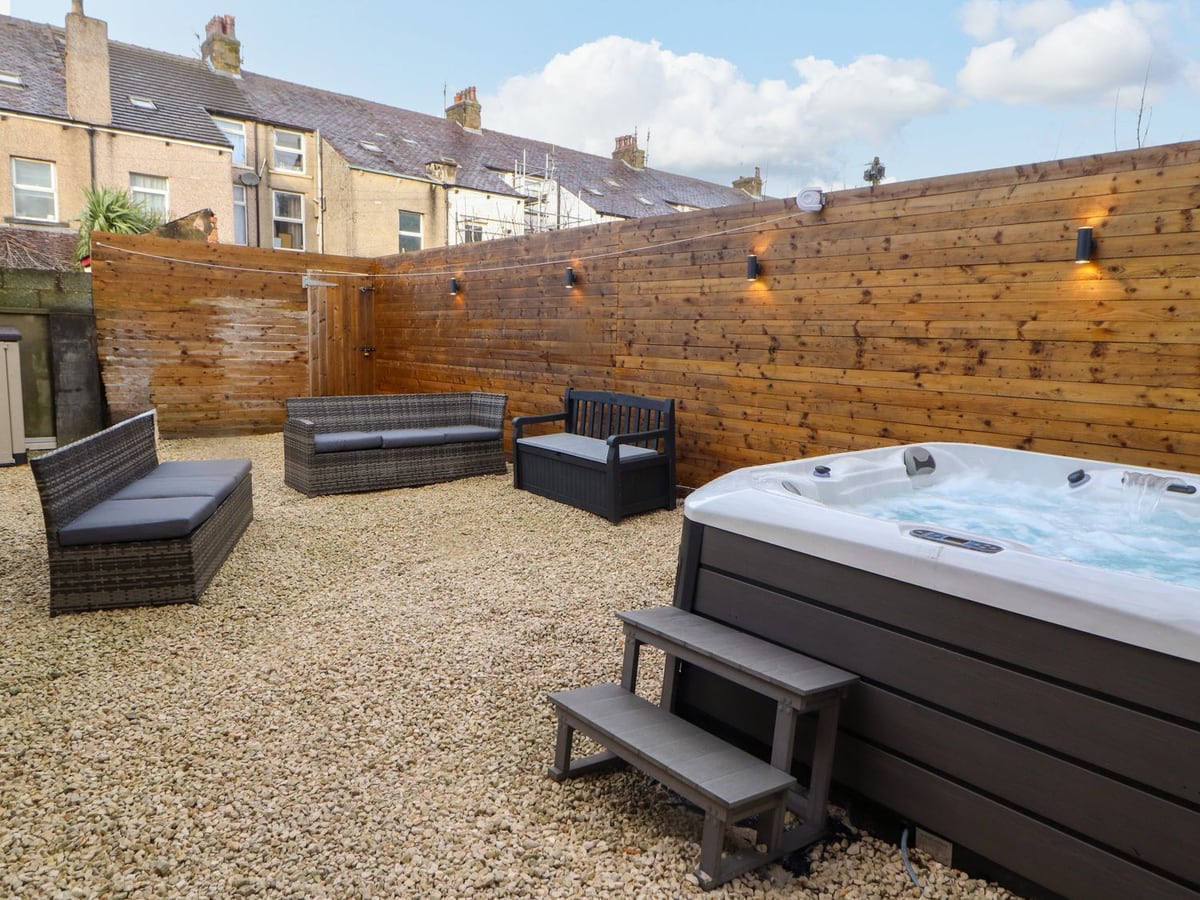 Inglemead gravel courtyard with hot tub, outdoor seating and tall timber fencing