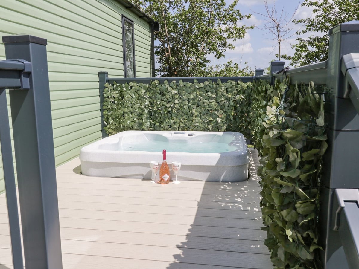 Hot tub on the side deck beside Jean's Place, with green cladding and leafy screens