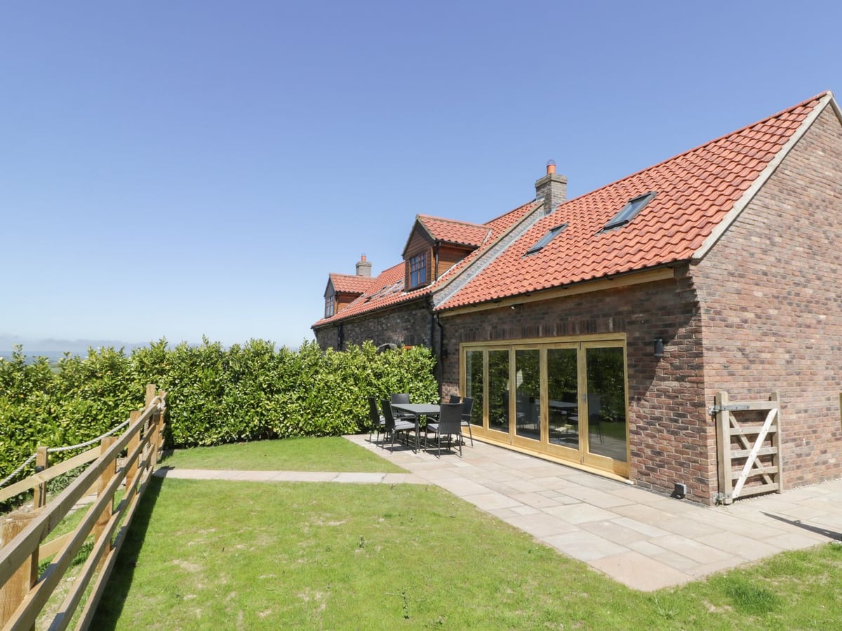 Patio table and chairs beside the brick exterior and windows at Kaitkyella Lodge