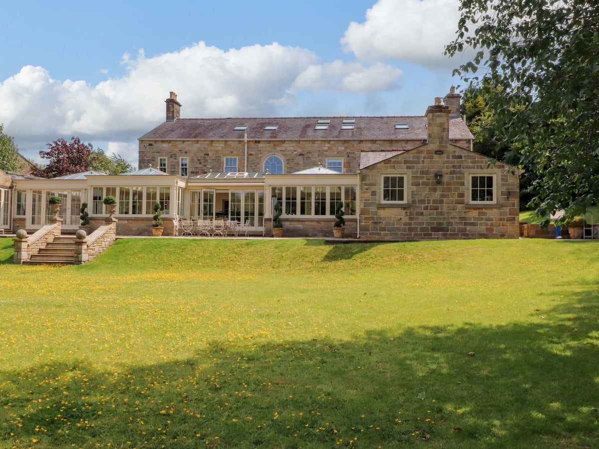 Laithe House stone exterior and conservatories above steps leading down to the lawn