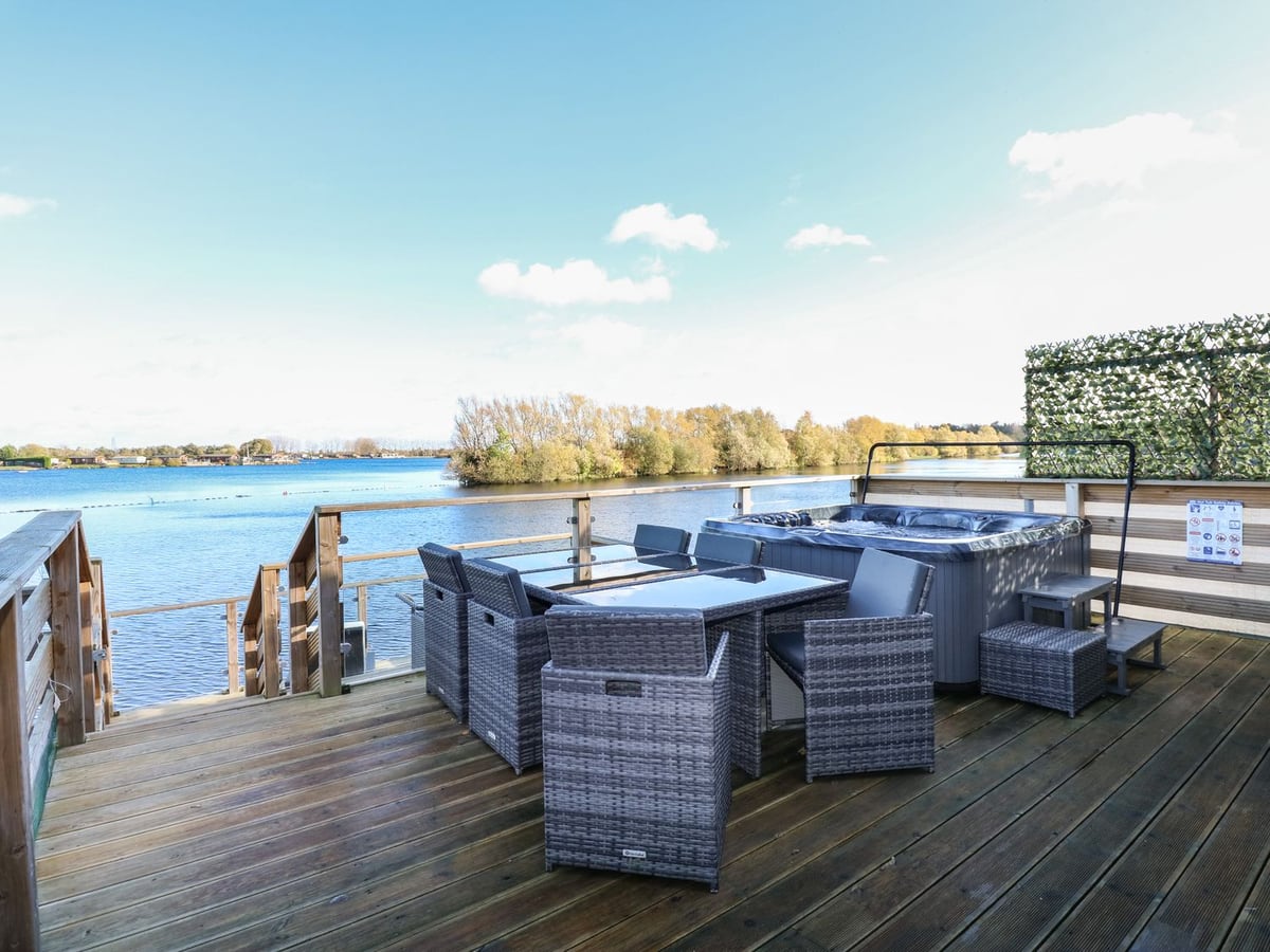 Lake View Lodge's waterside deck with dining chairs, hot tub and steps toward the lake