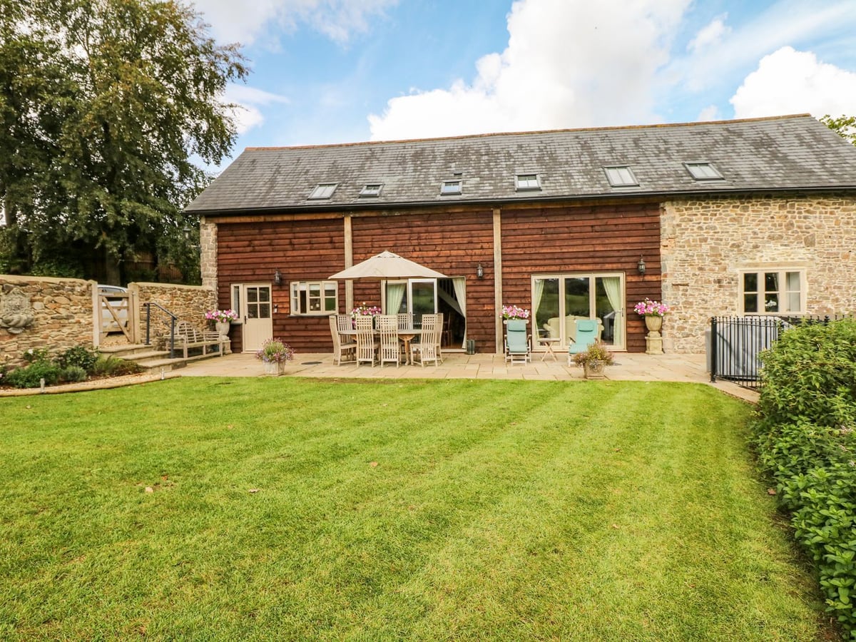 Stone barn with broad windows and a lawn outside the accommodation at Lake View