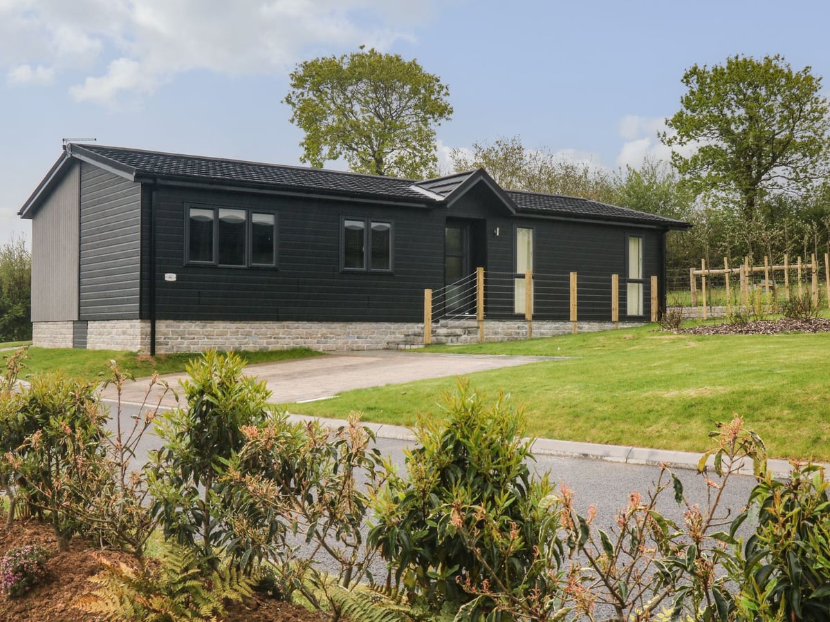 Dark timber lodge with entrance steps and open lawns around the accommodation at Lily