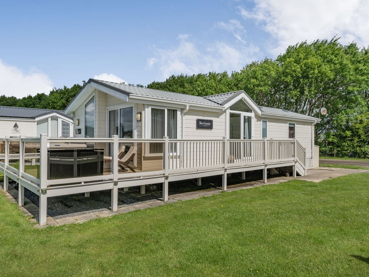 Links Lodge cream exterior with a raised deck and pale railings beside a lawn