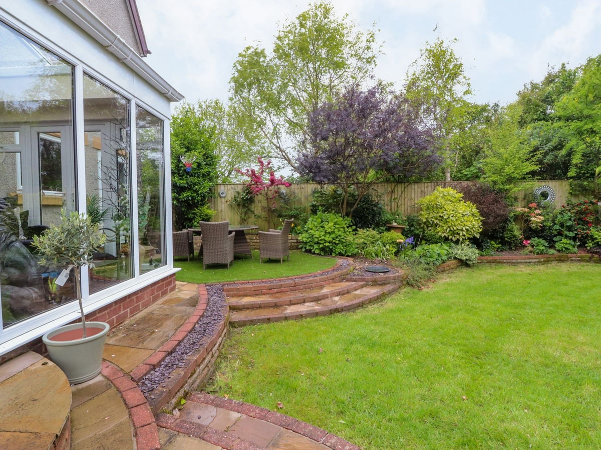 Linwood conservatory beside a lawn, planted borders and a stepped garden seating area
