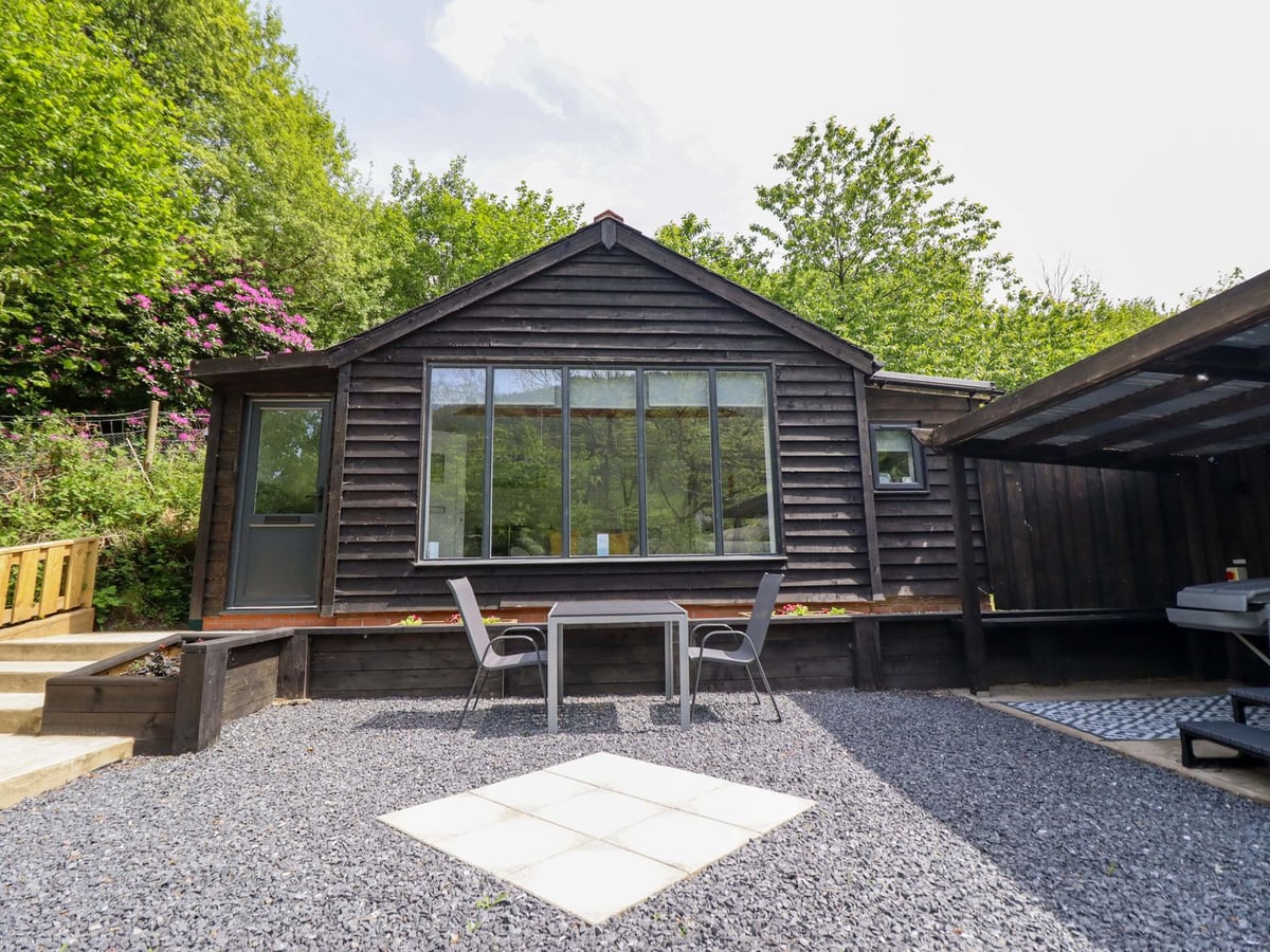Lodge at Nadur timber front with a gravel terrace, table and chairs, steps and roofed shelter