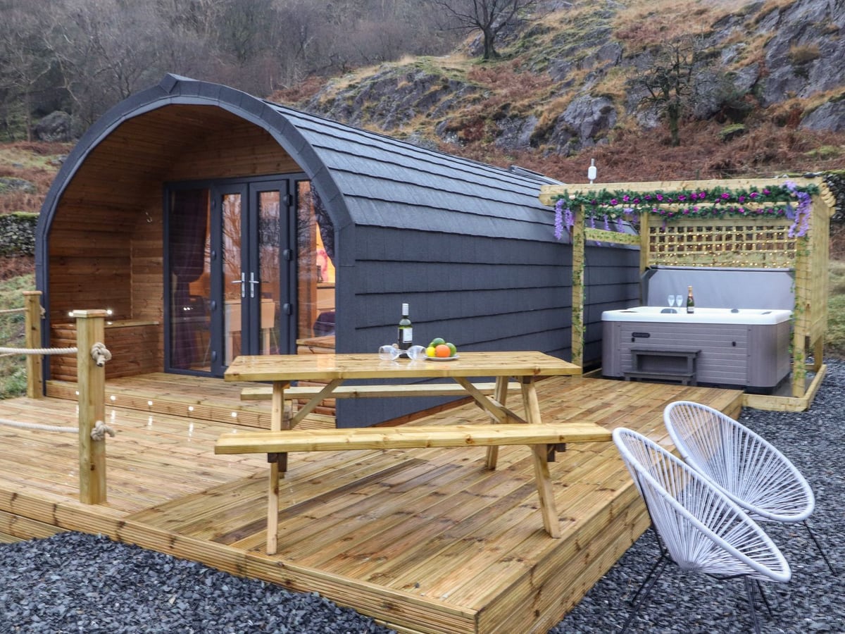 Lovies Place timber pod beside its hot tub, picnic table and deck with rope rails