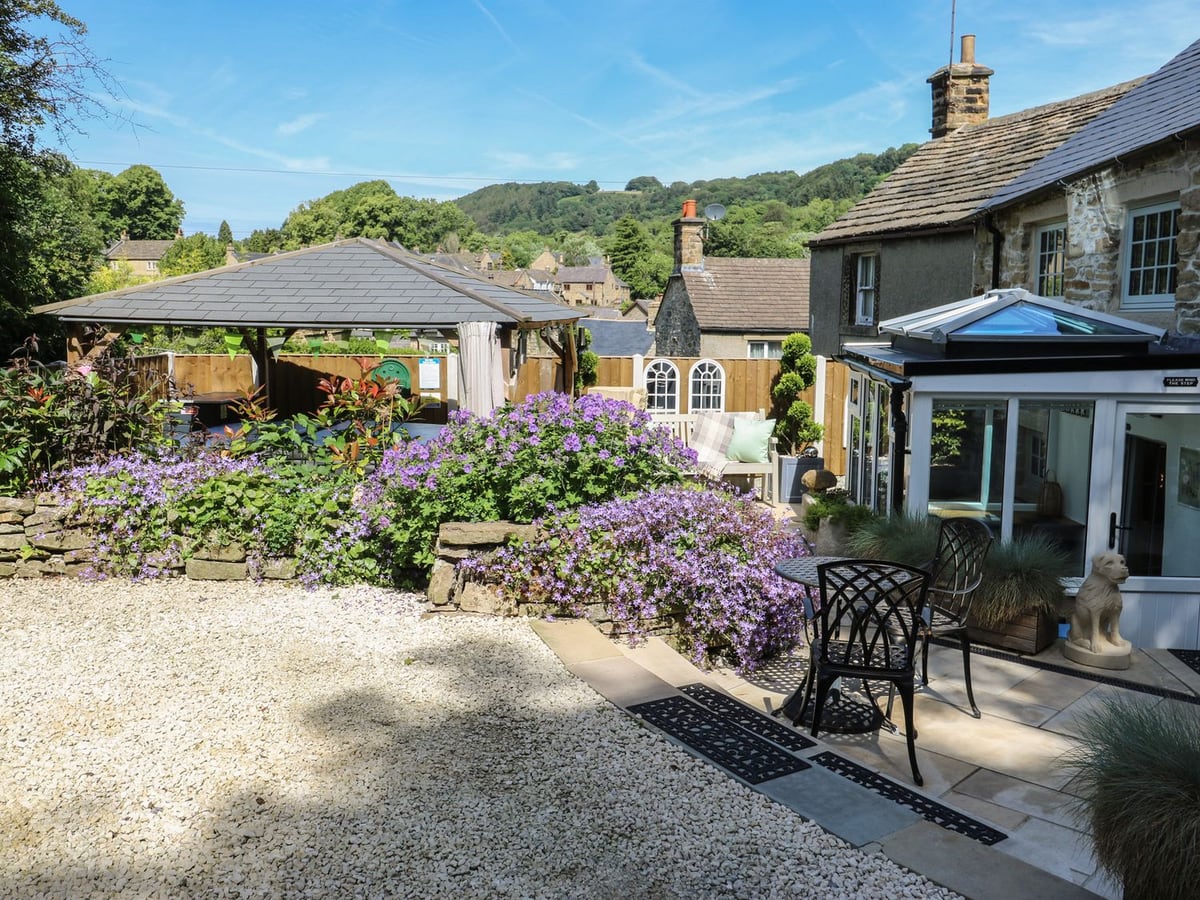 Lydgate Cottage with a gravel courtyard, flower beds, glazed porch and timber gazebo