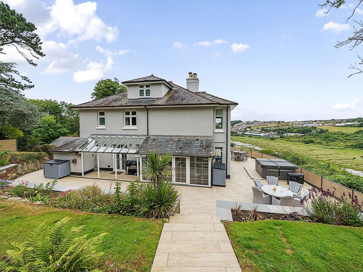House and glazed garden room beside a paved terrace, hot tub and estuary at Mallacleave House
