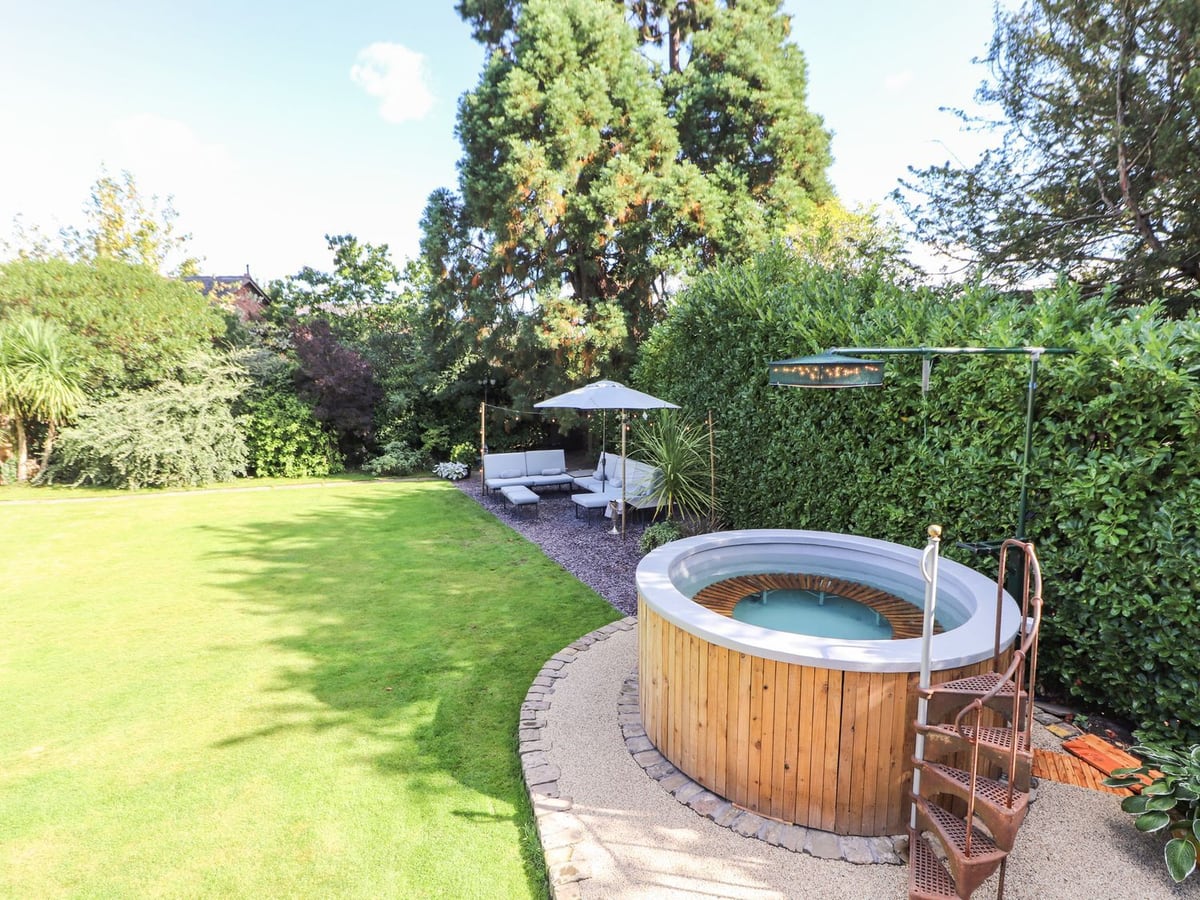Round hot tub beside the lawn and outdoor seating at Mickle Trafford Manor