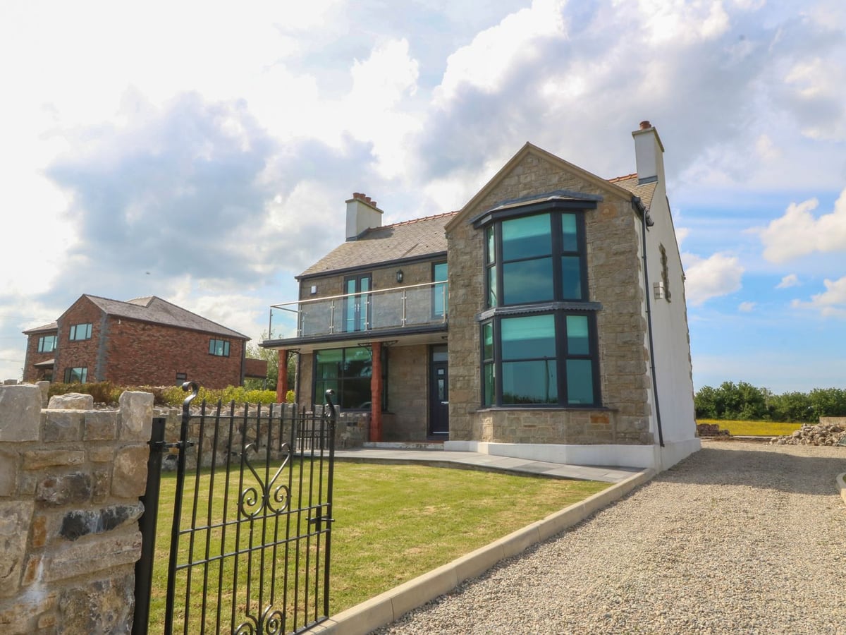 Morawelon stone-fronted house with a balcony, small lawn and gravel driveway alongside