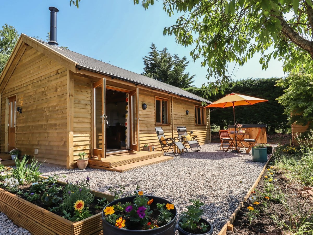 Timber cabin, planted beds and gravel seating area at Nelli Lodge at Mile End