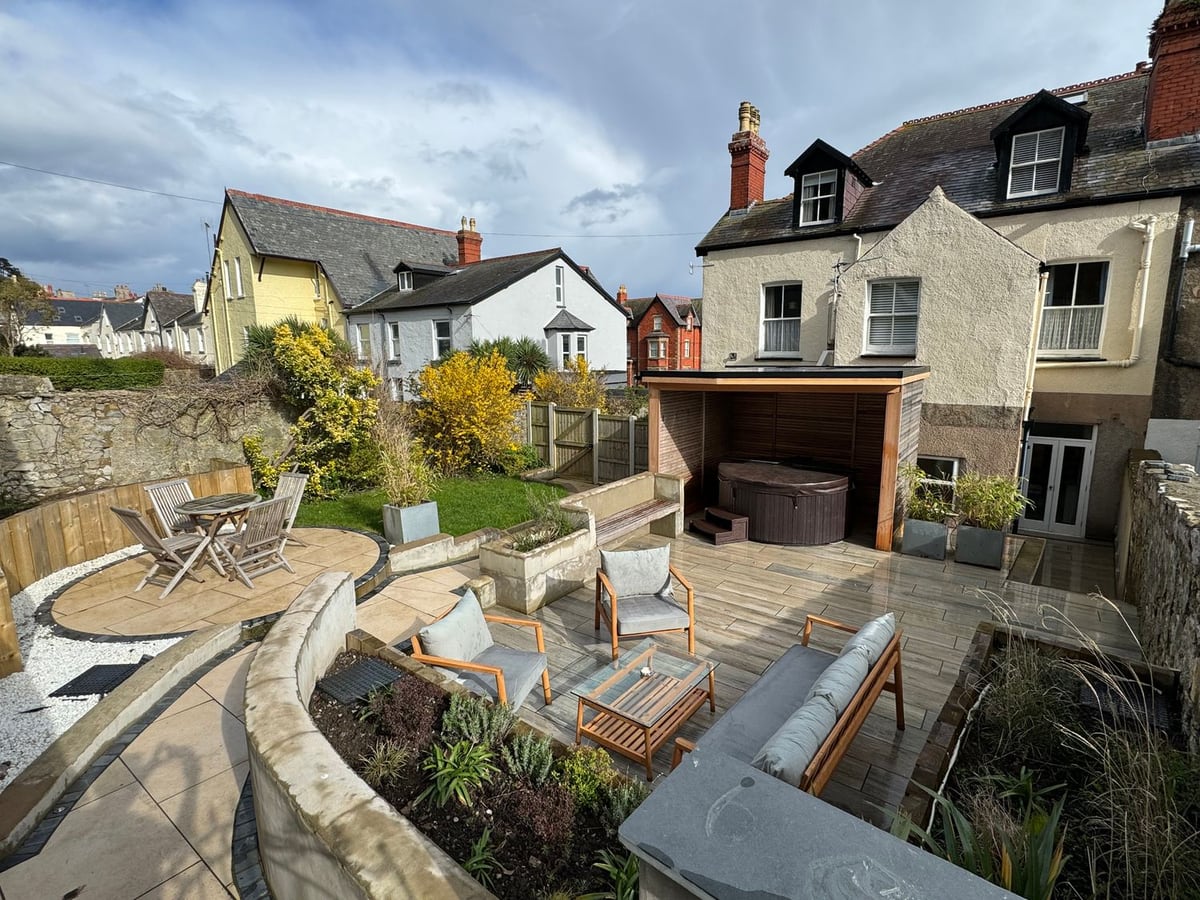 No.22 multi-level rear garden with patio seating, a hot tub under a timber shelter and a small lawn