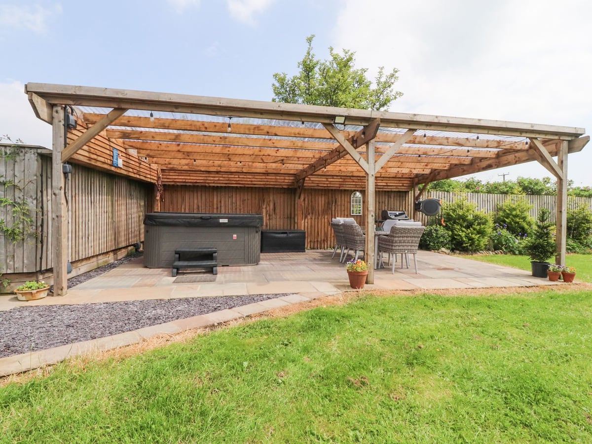 Covered hot tub and dining patio beside the lawn at Old Bell Works in Pilling