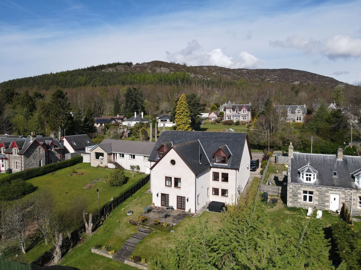 Old Distillery Lodge with a sloping lawn, garden steps and patio among neighbouring houses