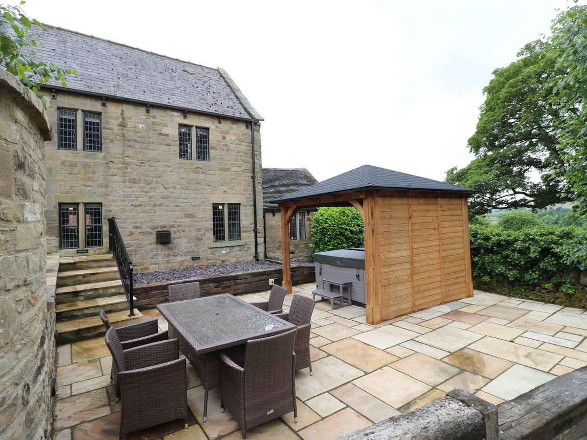 Orchard View stone exterior, paved courtyard, dining table and timber hot-tub shelter