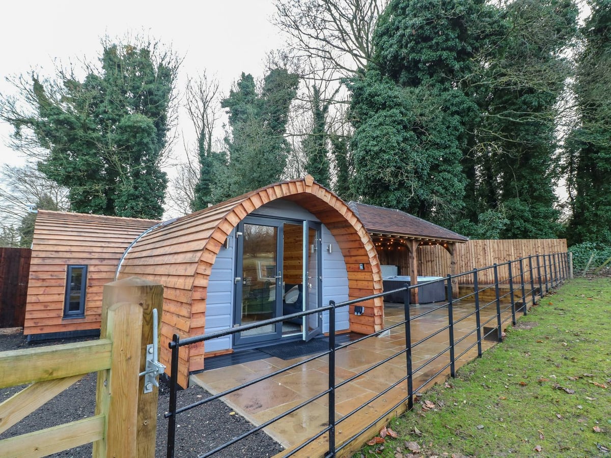 Timber Park View Lodge with curved roof, paved terrace, metal railing and covered hot tub