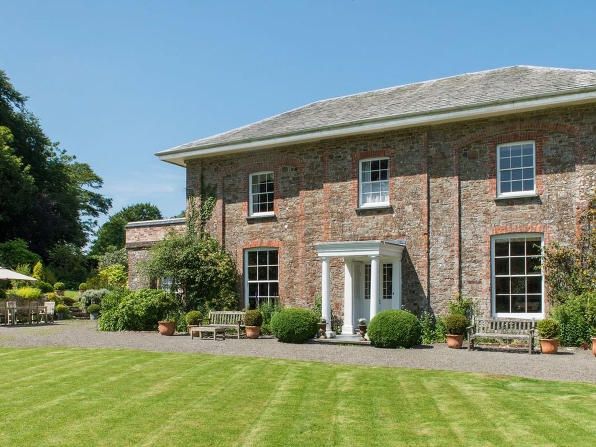 Stone country house with white sash windows and a columned entrance at Parnacott