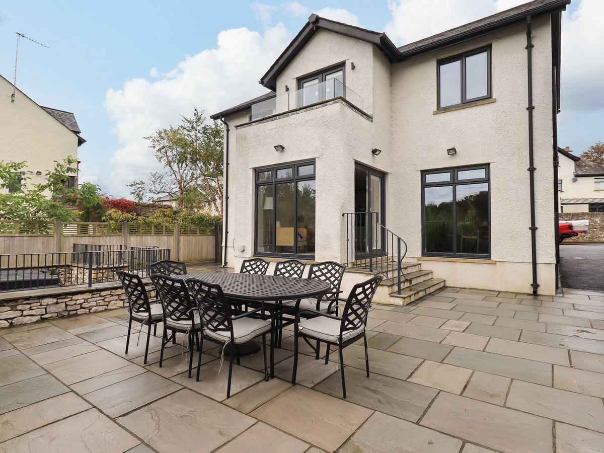 Pen-y-Ghent cream exterior beside a paved terrace with a large black outdoor dining table