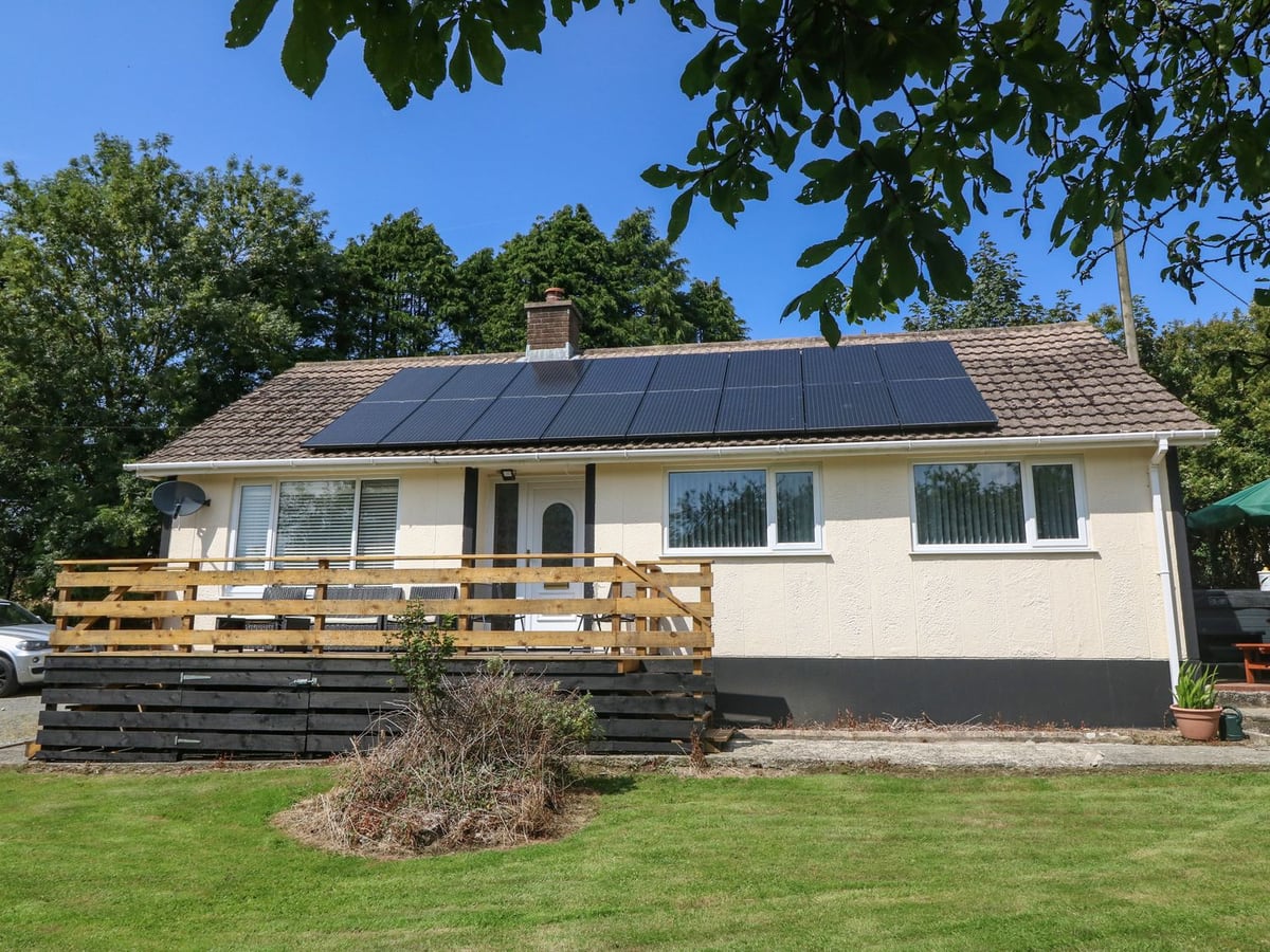 Petlyns Patch bungalow with lawn, solar panels and a raised wooden deck outside the door