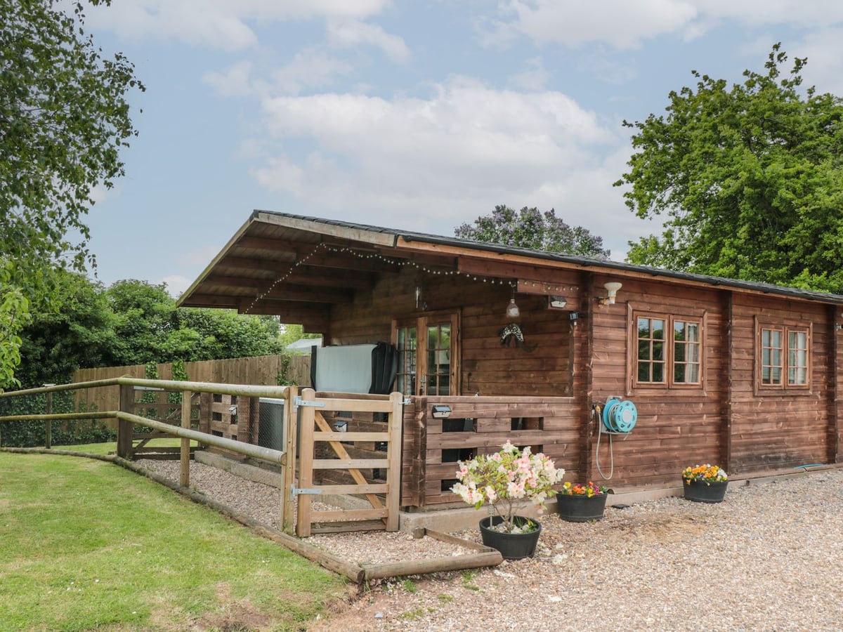 Timber cabin with a covered veranda, hot tub and gravel approach at Pigsfoot Lodge