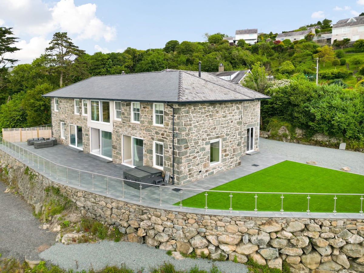 Plas Amherst stone house with a hot tub on a paved terrace and an artificial lawn beside it