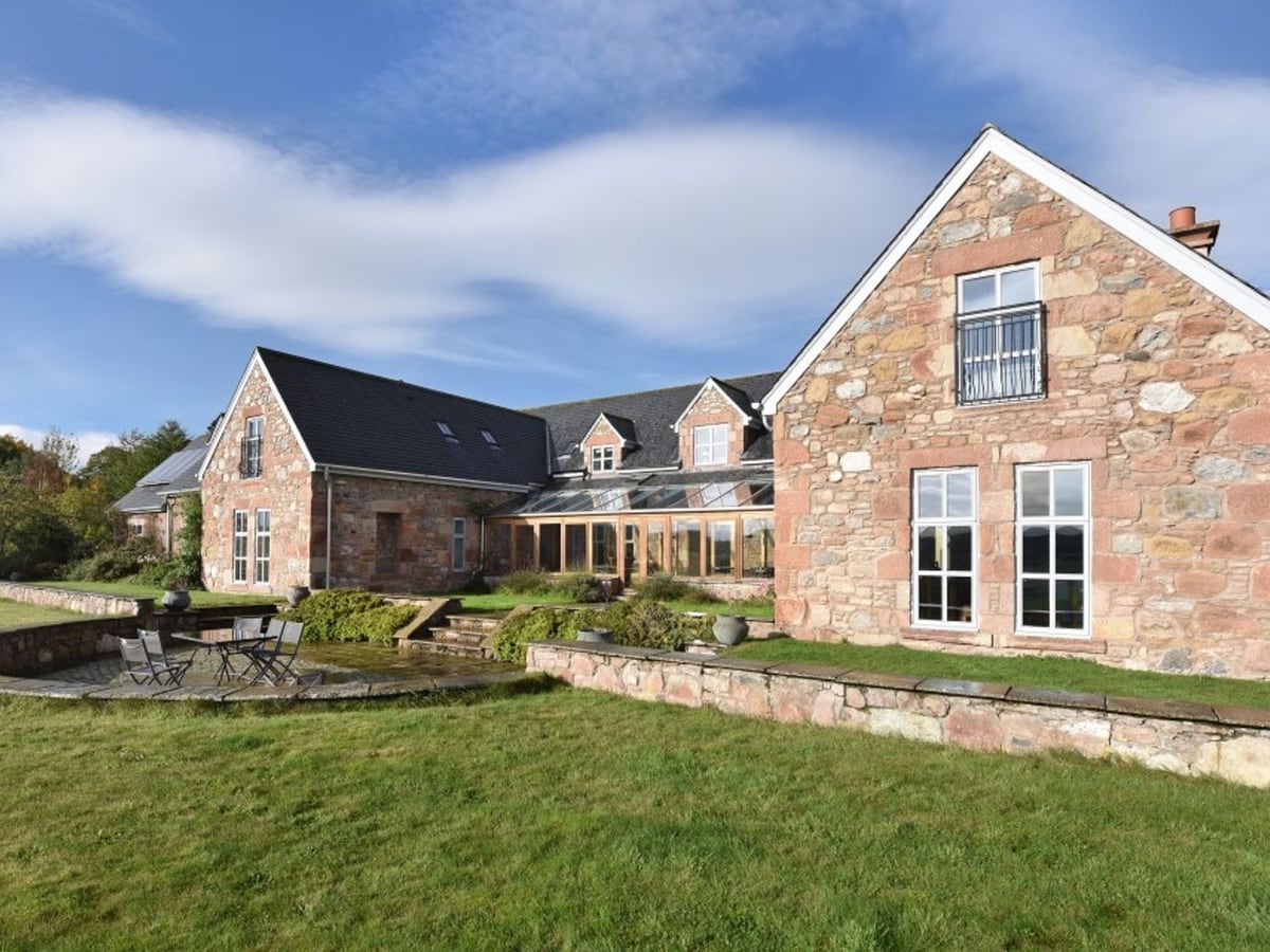 Quarryfield stone house with a long conservatory, garden steps and outdoor table beside the lawn
