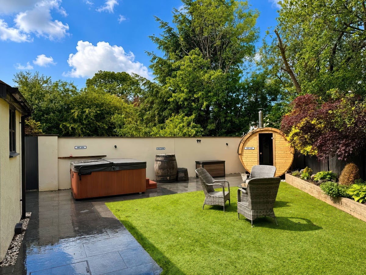 Railway Cottage walled garden with artificial grass, chairs, barrel sauna and hot tub with its lid on