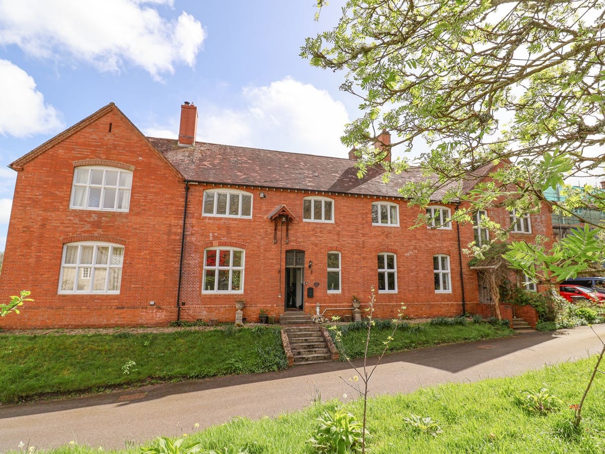 Red-brick house with white windows and entrance steps above a paved approach at Red House