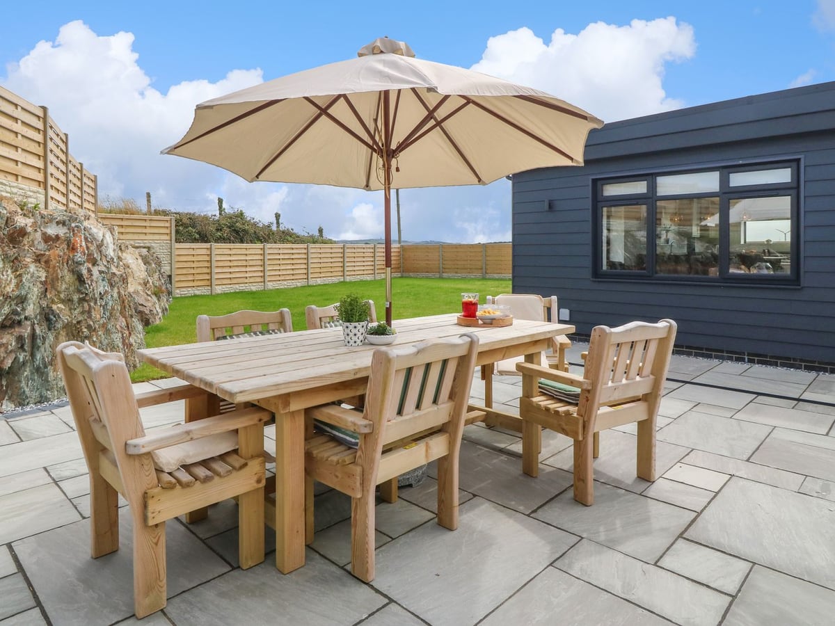 Refail Fach patio table and parasol beside the dark-clad extension, with lawn beyond