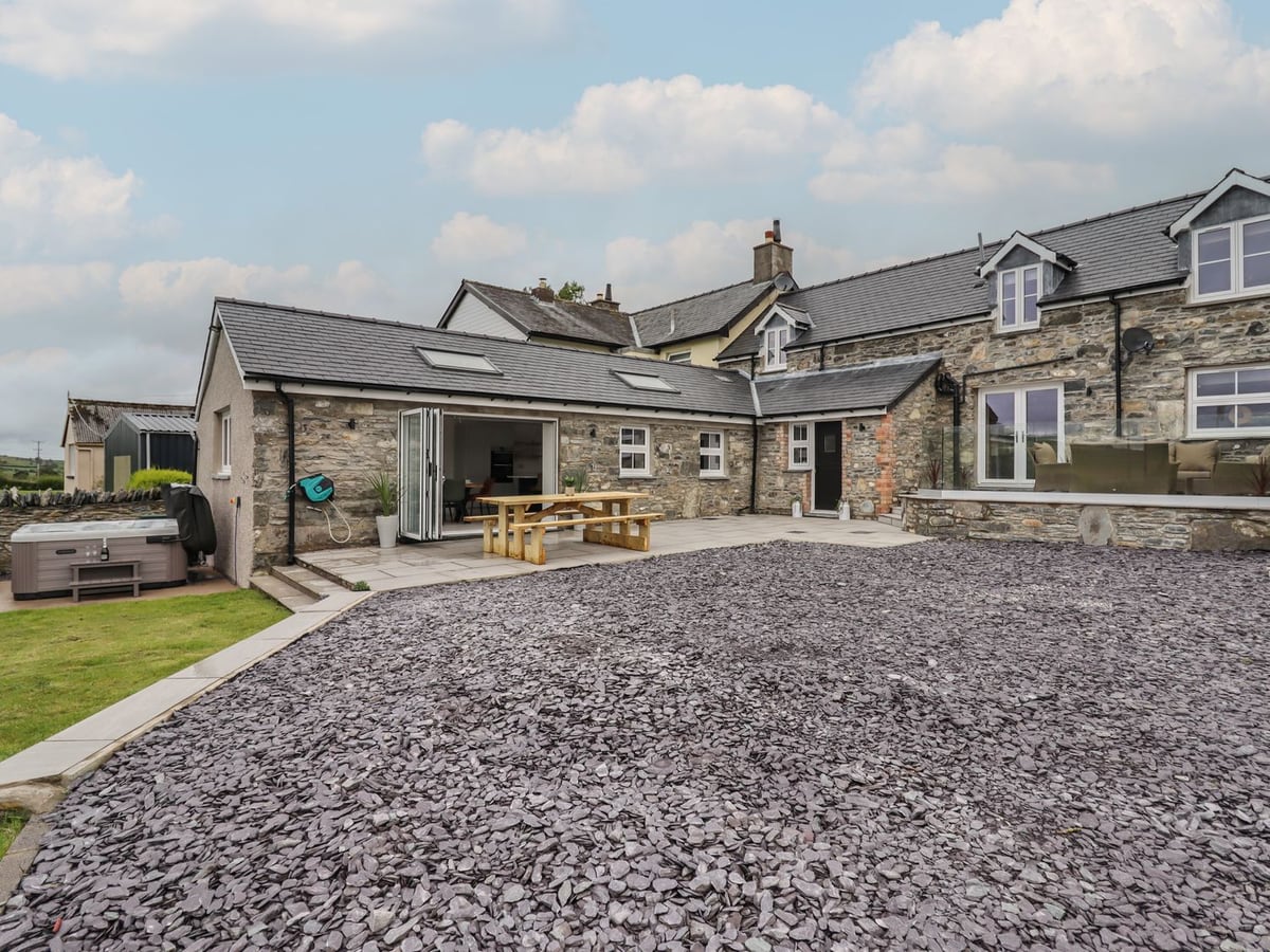 Stone cottage with patio picnic bench, raised glass-edged terrace, hot tub and slate gravel yard