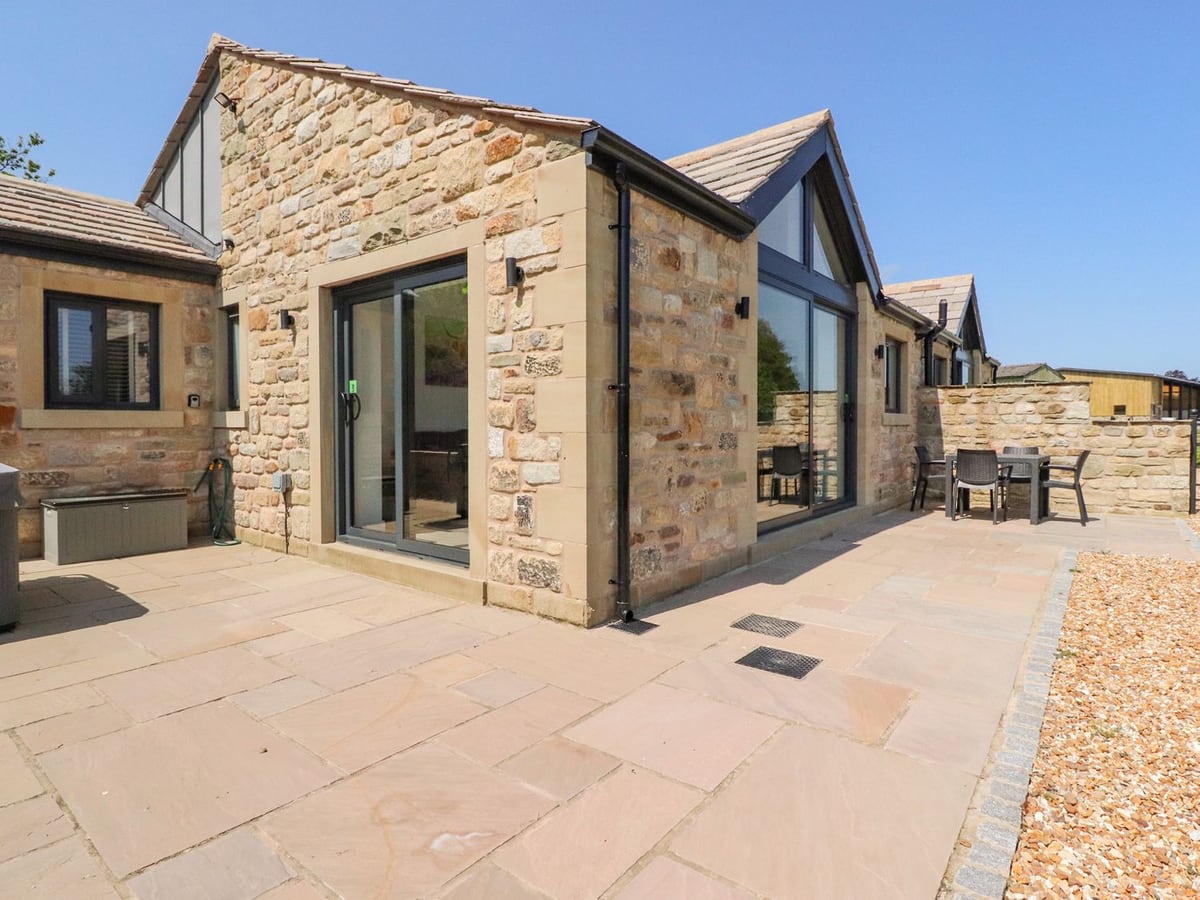 Ribble View stone cottage with glazed doors, a paved patio and outdoor dining table