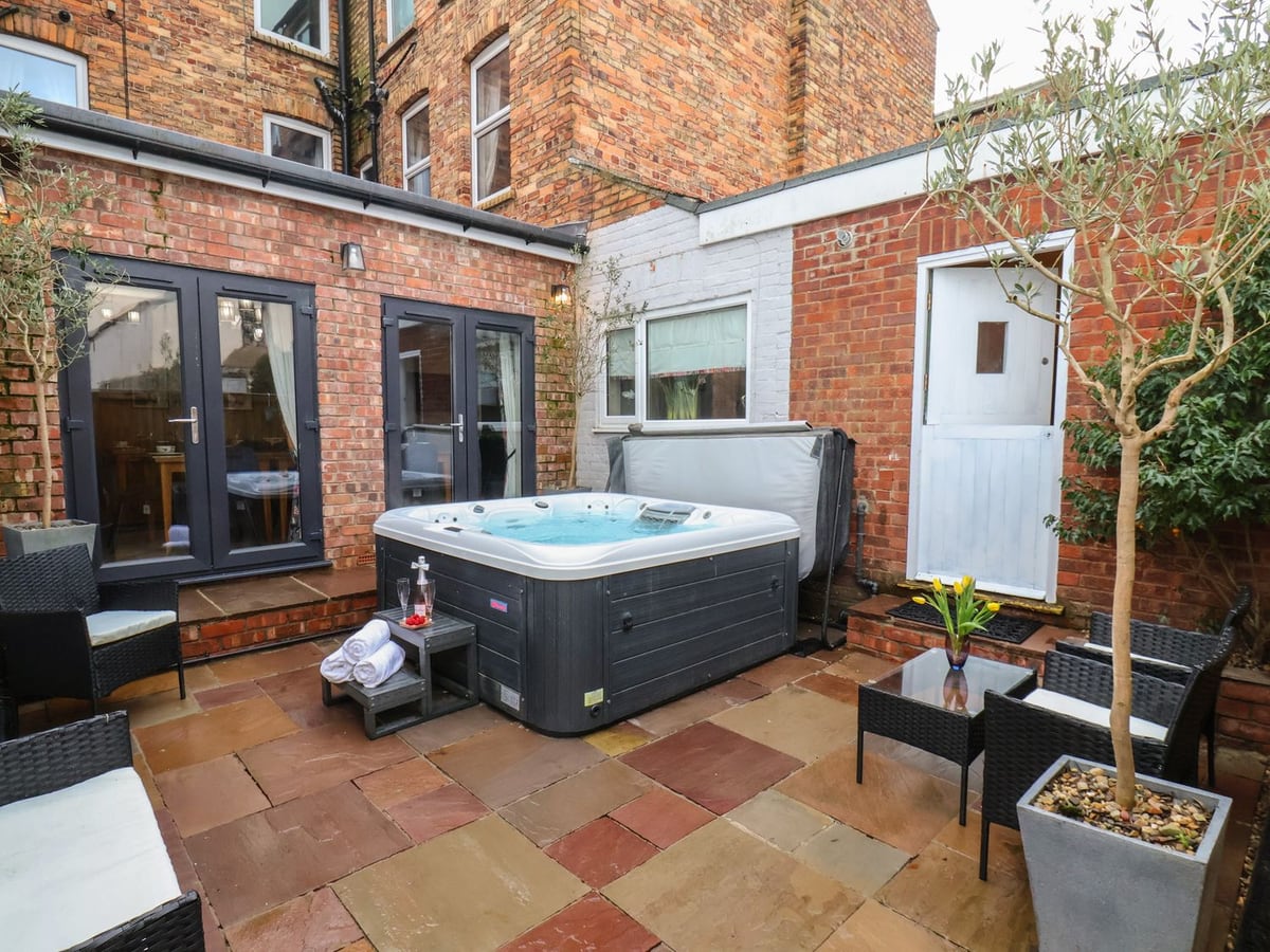 Patio hot tub and seating beside the brick exterior at Rutland Grange in Filey
