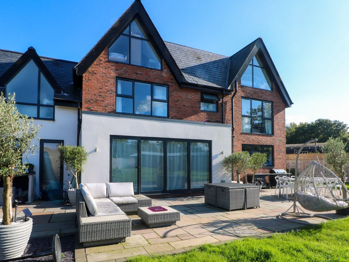 Brick exterior, patio seating and a strip of lawn beside the terrace at Rye Croft