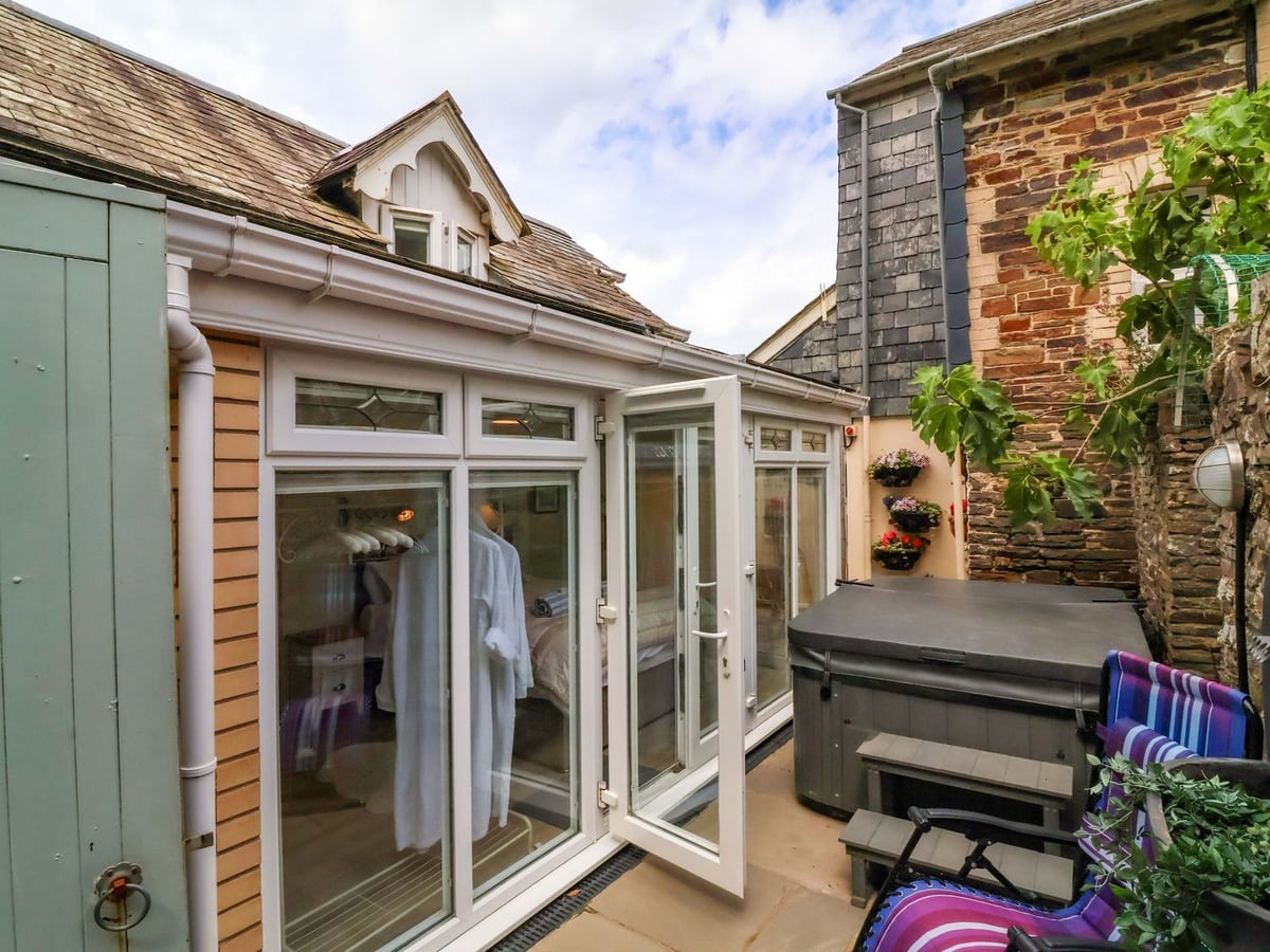 Glazed doors beside a covered hot tub in the narrow stone-walled courtyard at Sea Sanctuary