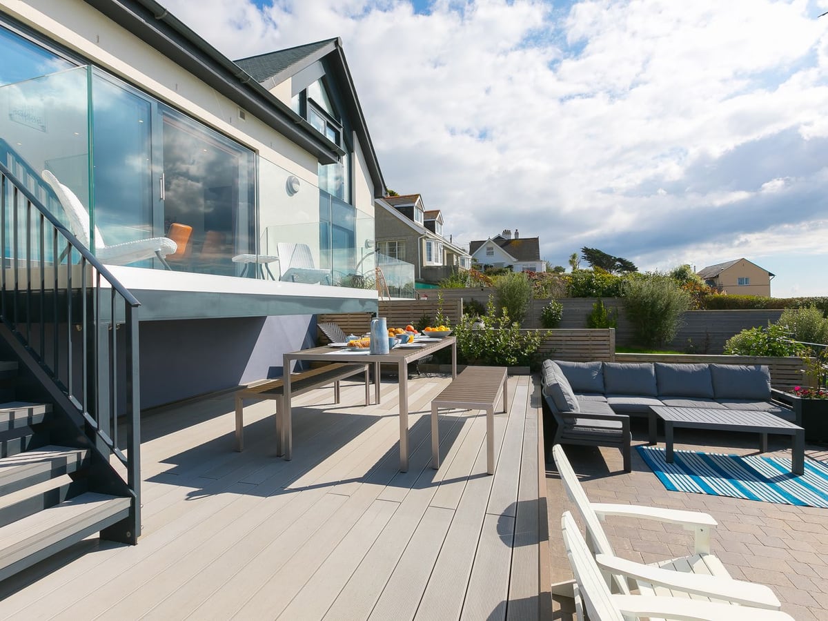 Sea Sands' glass-fronted exterior with steps to a deck, dining table and lower patio seating