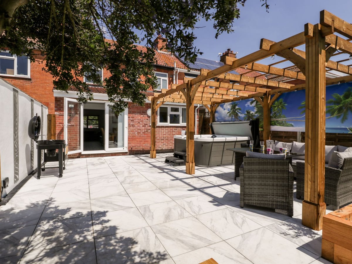 Seacider patio with pergola seating and hot tub outside the brick house