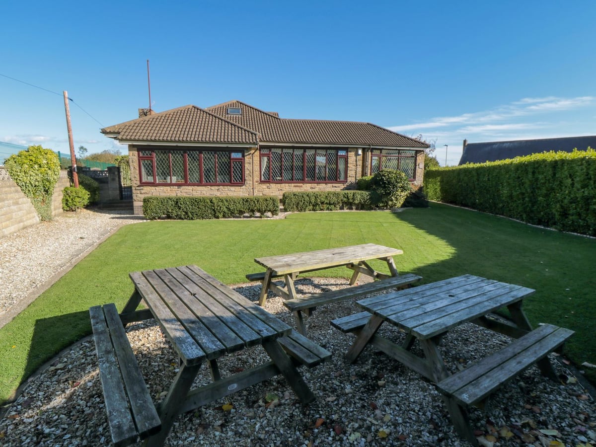 Lawn garden with picnic tables and hedges beside the house at Seacrest Lodge