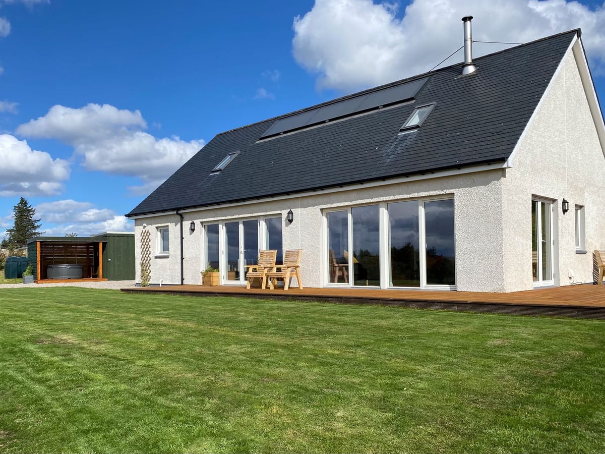 Sealladh Mor with a broad lawn, timber deck and covered hot tub beside the house