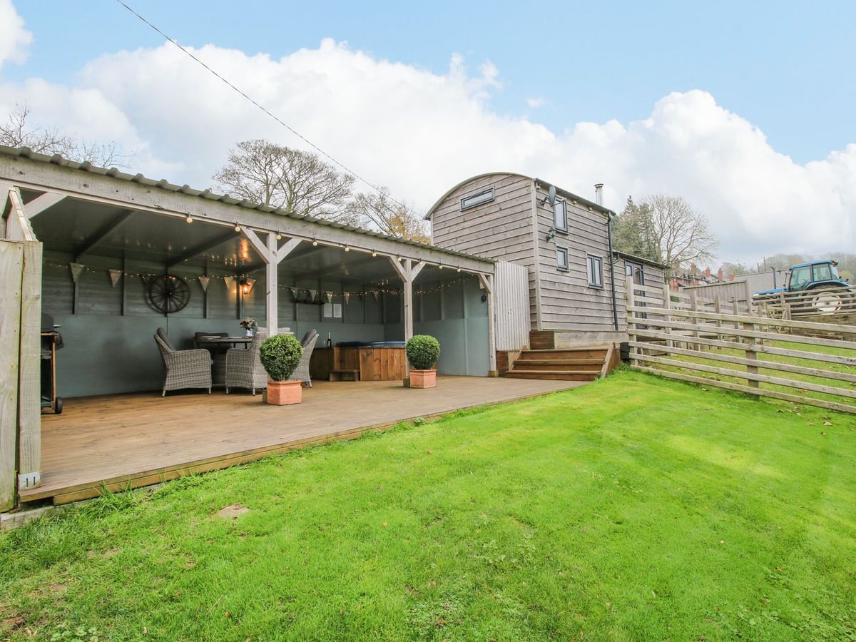Shepherds Cabin at Titterstone with lawn, steps and a covered deck holding seats and a hot tub